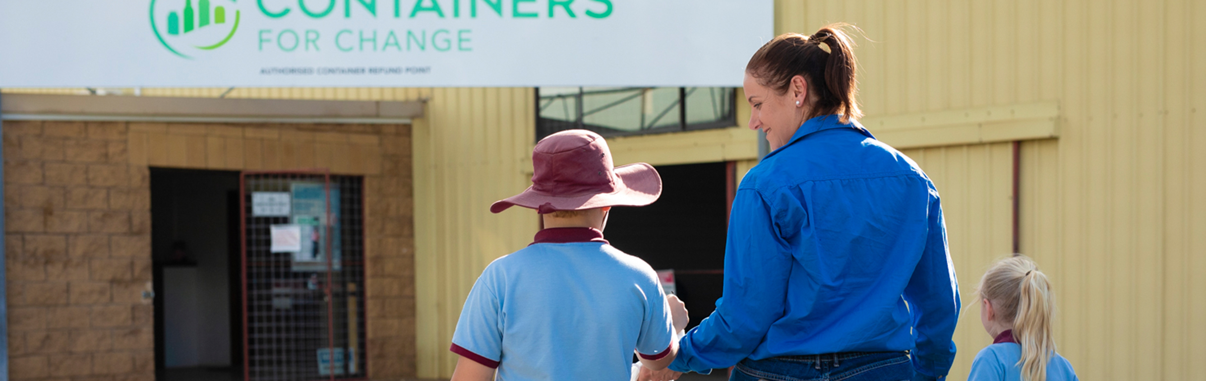 Woman and kids walking towards recycling depot